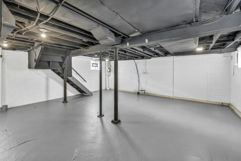 Bodenplatte oder Keller: unfertiger Keller mit Balken, Stützen und Treppe im Rohbau