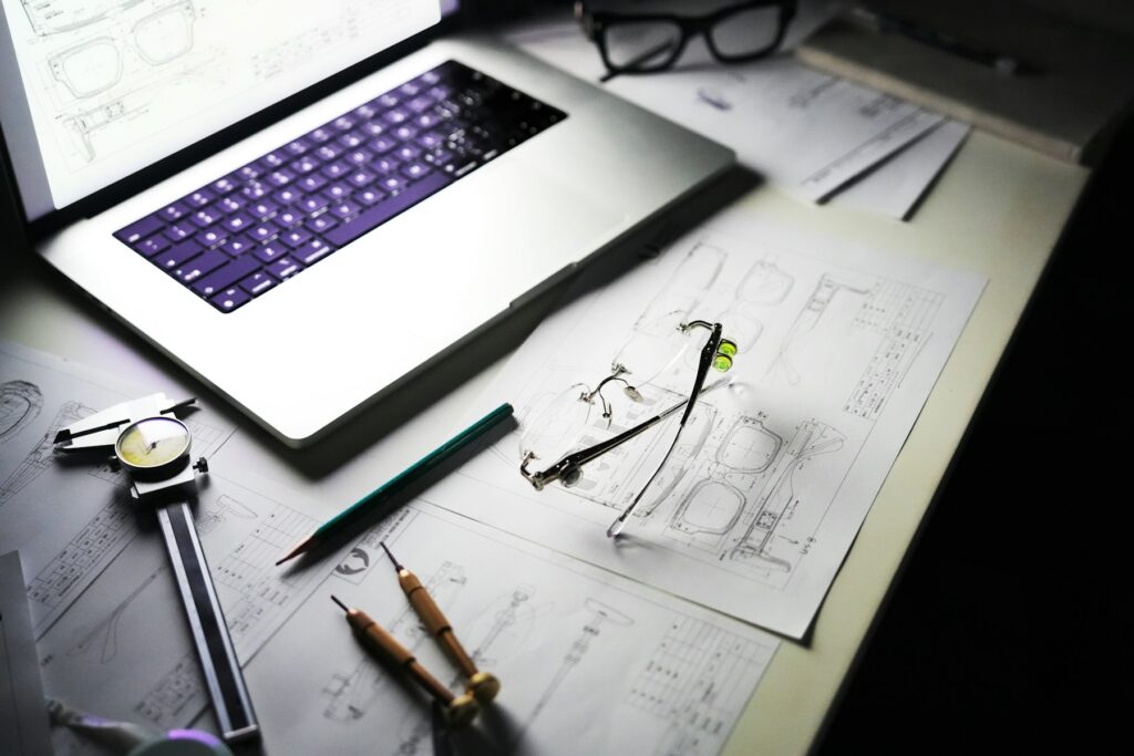 Hausbau Kosten kalkulieren: Schreibtisch mit Laptop, Bauplänen und Werkzeug