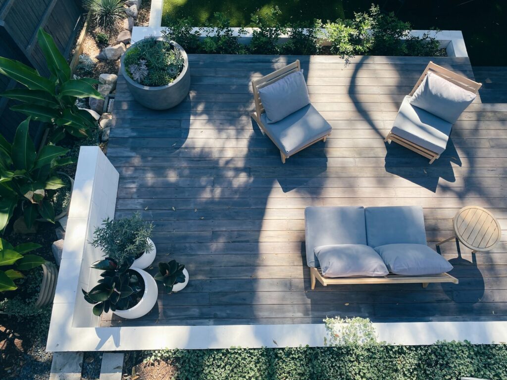 Holzterrasse bauen: Holzdeck mit Gartenmöbeln und Topfpflanzen von oben fotografiert