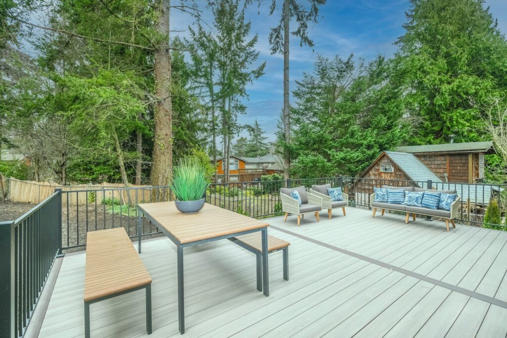 Holzterrasse bauen: Holztisch und Stühle auf einem gepflegten Holzdeck im Garten