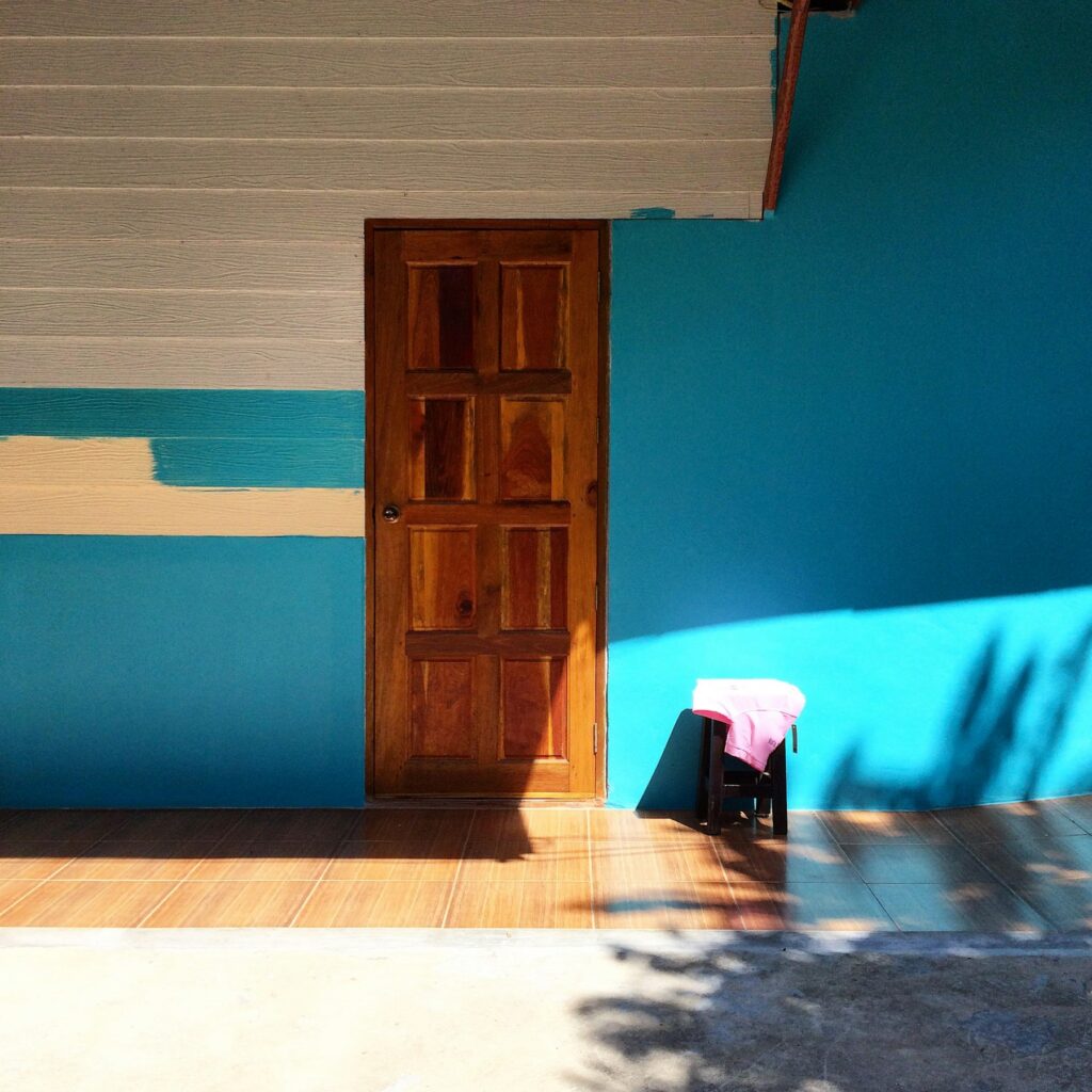 Wandfarben Trends 2027: Holzregal mit Deko vor einer gedeckt blauen Wand