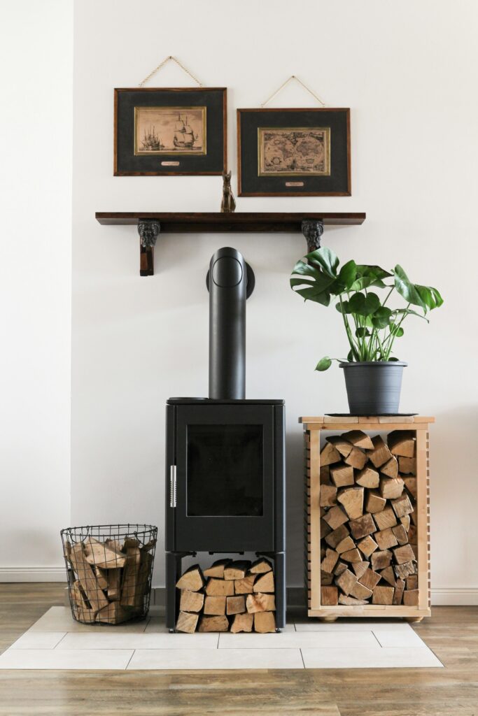 Wohnzimmer mit Kamin: schwarzer Kaminofen neben einem Flechtkorb für Brennholz